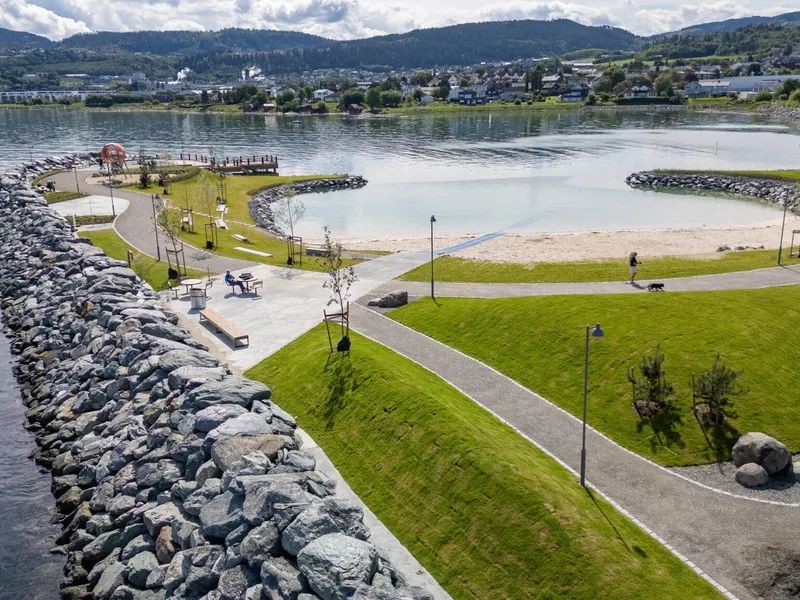 Dronebilde som viser hele strandområdet, avskjermet med en molo bygget av naturstein. Foto: Asplan Viak