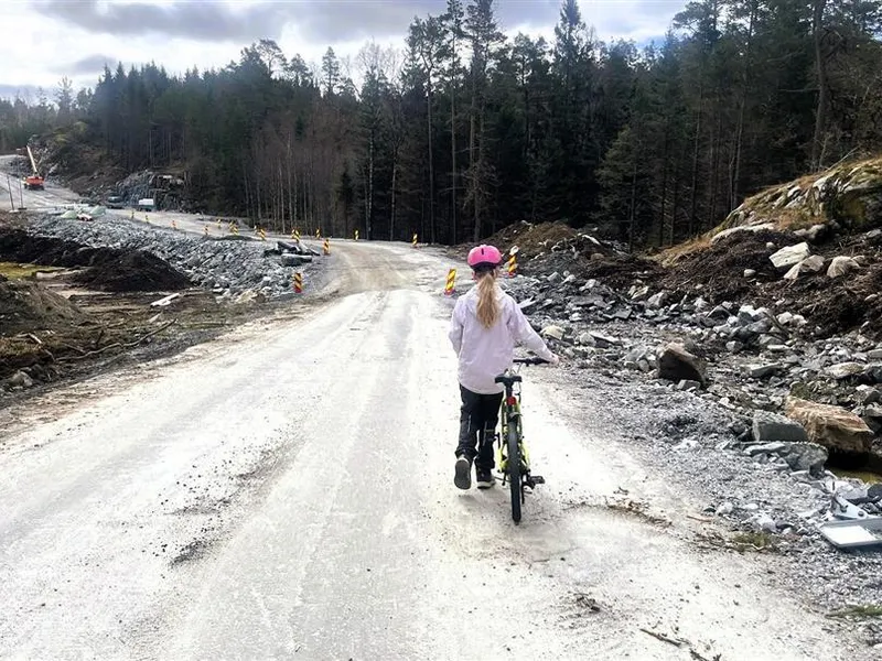 Jente triller sykkel ned en bakke i et veiarbeidsområde - Klikk for stort bilde