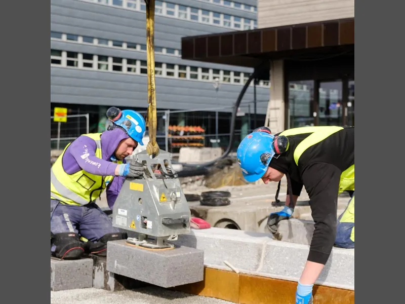 To steinleggere bruker løfteutstyr til å legge steinheller. Foto - Klikk for stort bilde