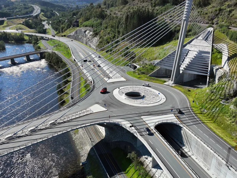 Tunnelen skal gå fra Nydalsbrua og rett inn i fjellet til Byåsen i Trondheim. Tunnelportalene står allerede klare, der brutårnet står i midten.. Dronefoto: Skanska.