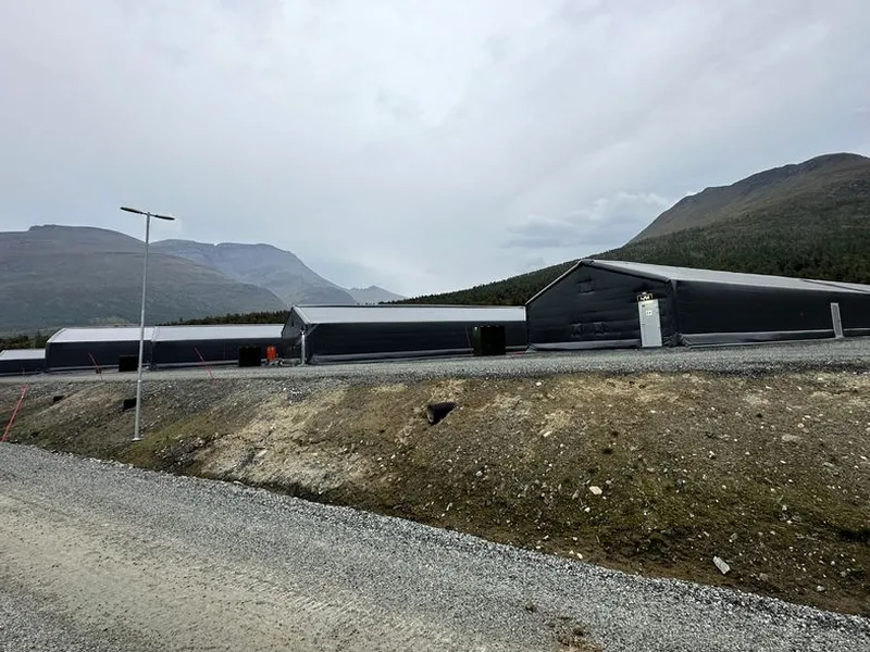 Bildet viser permanente forlegningstelt i en camp for alliert øving og trening, med fjell i bakgrunnen.