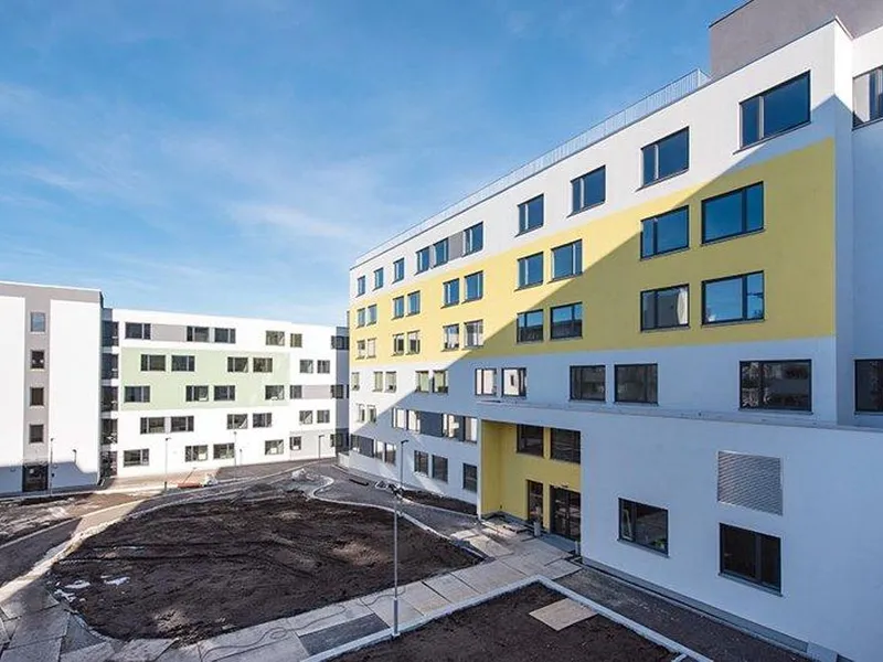 Foto av lyse bygg i seks etasjer, vinduer, bakgård mm