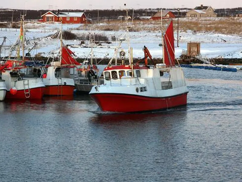 Foto. Rød og hvit sjark går inn til havna