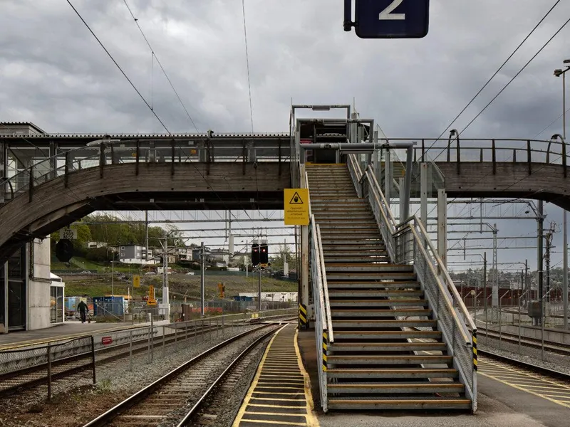 Overgangsbru over toglinjen på Moss togstasjon. Bygget i tre. Bildet viser spor to og tre. Grå himmel.