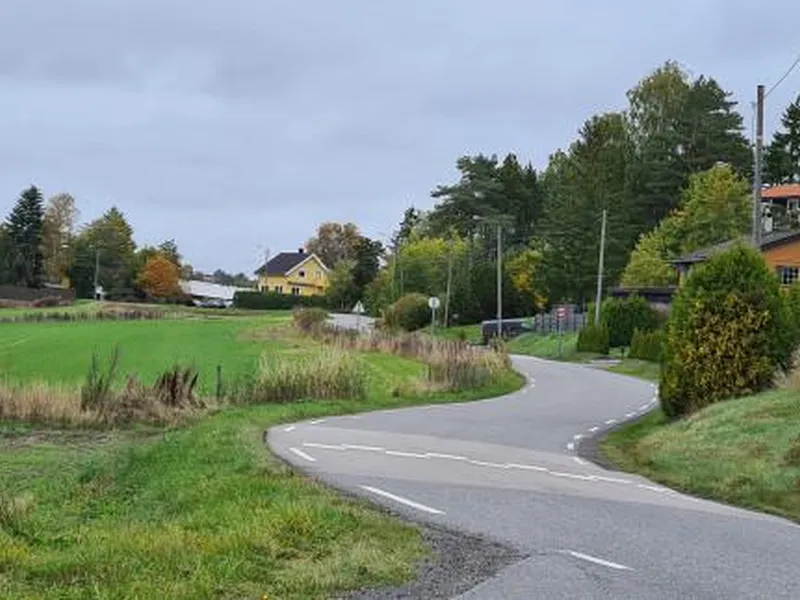Bildet viser  landbruksareal på den ene siden og private boliger på motsatt side