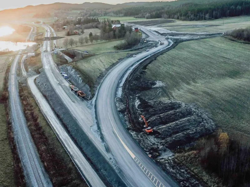 Dronebilde fra strekningen. Rasområdet er til venstre bak i bildet, og den midlertidige veien går på oversiden av bebyggelsen. Foto: Letnes Entreprenør AS.