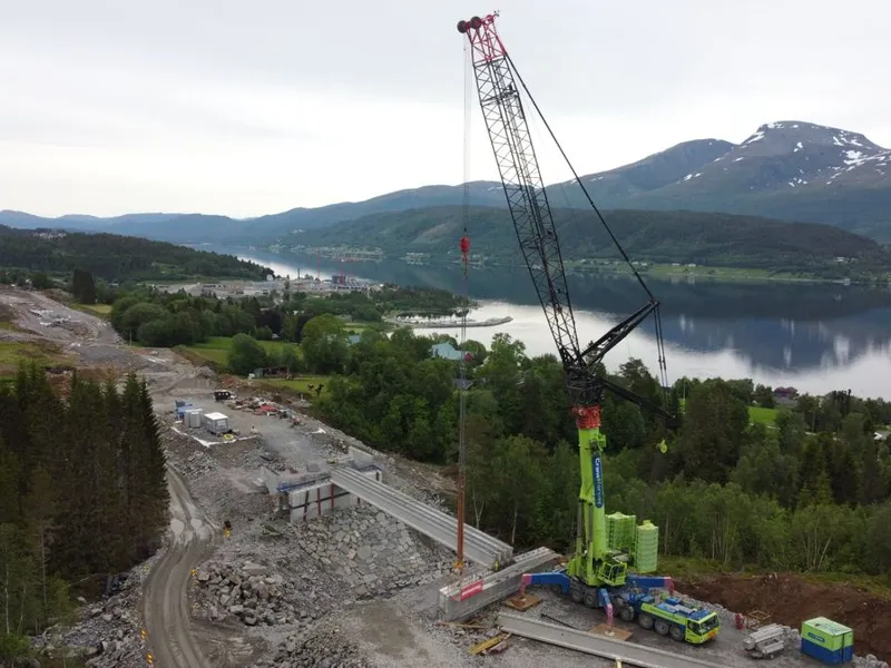 Montering av 40 meter lange prefab-bjelker på bru over Hagaelva. Til venstra for krana midt på bildet ser vi det nye sykehuset på Hjelset som er under bygging. Bildet er tatt sist sommer. Foto: Statens vegvesen