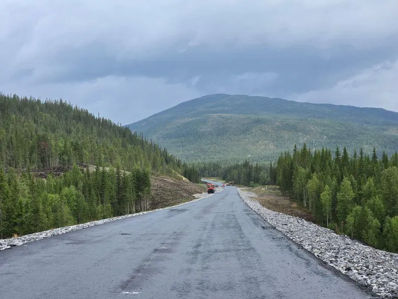 Bildet viser en lang slak bakke som nylig er asfaltert. Bilteteksten sier, Asfaltert: Store deler av den en mil lange vegstrekningen har fått asfalt. Vegen er 9,5 m bred og får fartsgrense 90 km/t.