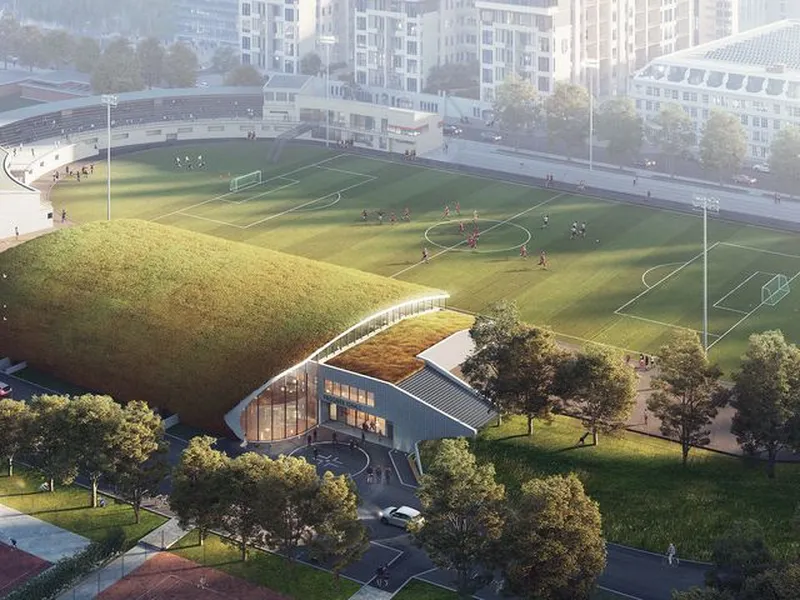 Det er tatt arkitektoniske grep for å integrere den nye hallen i landskapet på en god måte. Det buede taket er dekket med grønt mosebelegg, og følger fint landskapsformen på den vollen som allerede ligger her. Illustrasjon: Dyrvik Arkitekter AS