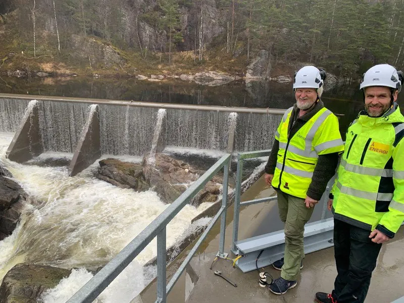 Dam, vann, to mennesker i vernetøy. Foto.