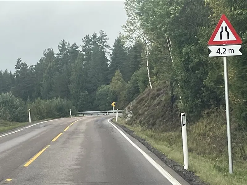 en vei med gul stiplet linje i midten og et varselsskilt på høyre side - Klikk for stort bilde
