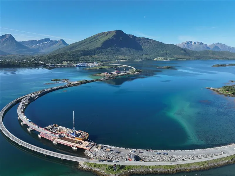 Fjord, fjell, lav bru med anleggsaktivitet. Høy bru i bakgrunnen.  - Klikk for stort bilde