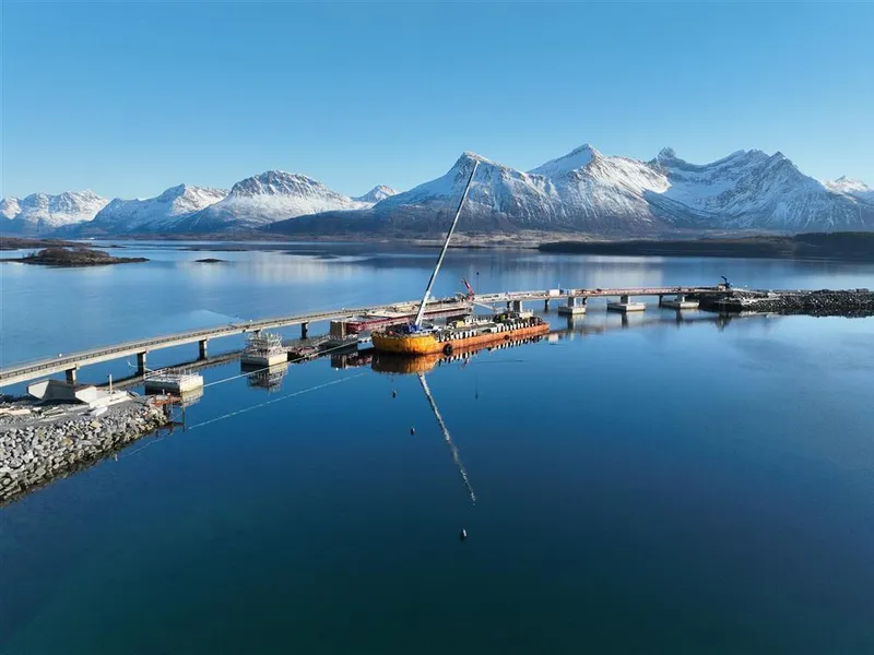 Lav bru, stor lekter, anleggsaktivitet. Stille fjord og snøkledte fjell. Foto - Klikk for stort bilde