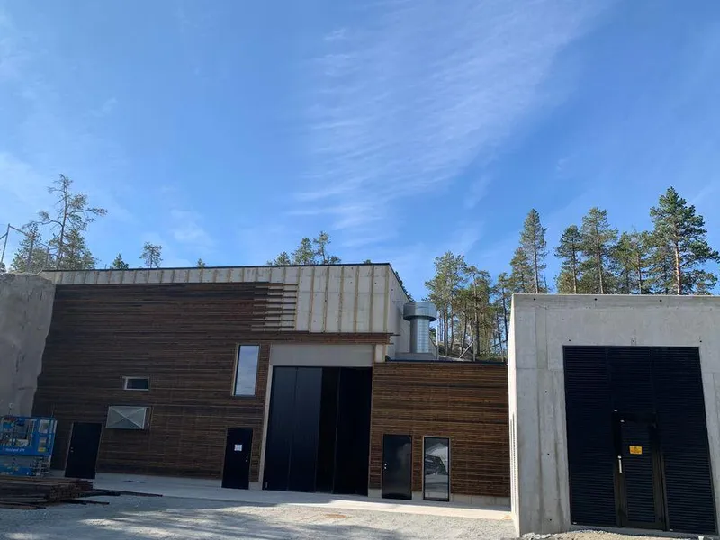 Kraftverksbygg, himmel, skog. Foto.