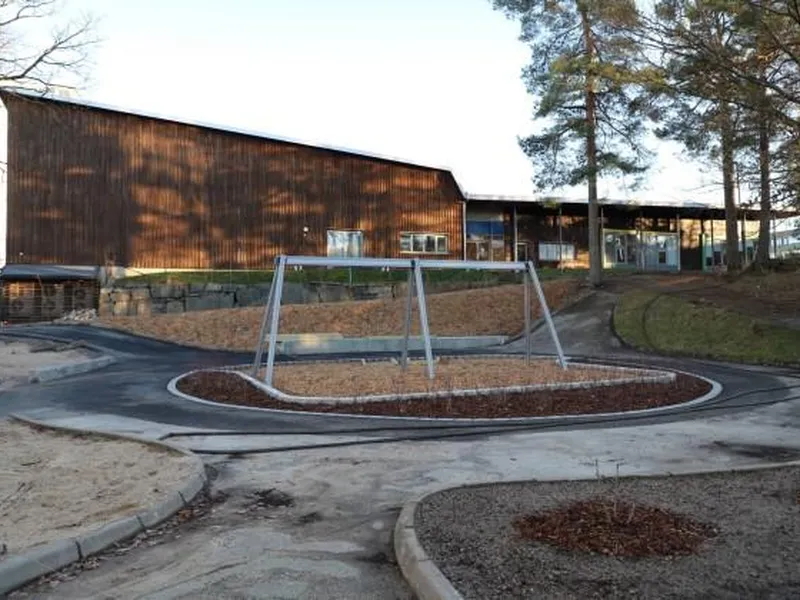 Lekeområdet med skolen, som skal bli barnehage, i bakgrunnen.
