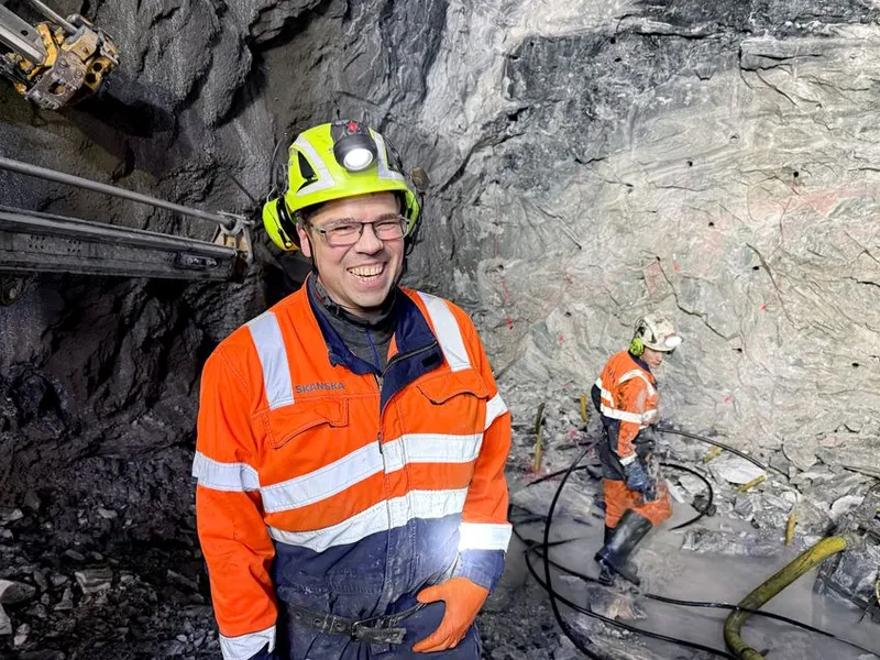 Bildet viser  sprengningsbas Tore Gunnar Gundersen med lærlig Trond Randen i bakgrunnen, som lader ferdig borede hull i fjellveggen (stuffen) og gjør klart til sprengning.