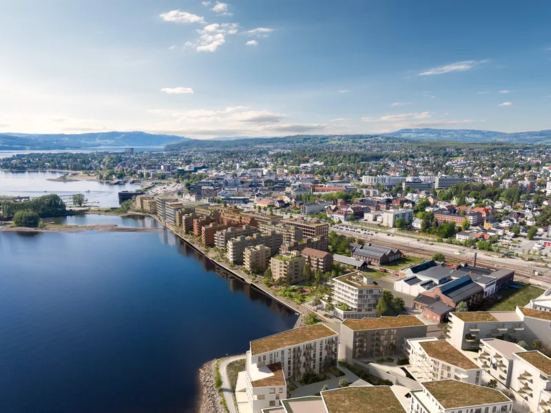 dronebilde med illustrasjoner av nye bygg ved sjøkanten av Mjøsa. Like ved stasjonen.