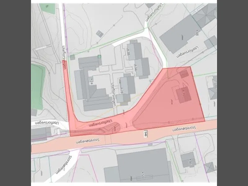 Kartutsnitt som viser område markert med raud farge, omgitt av bygningar og veg.