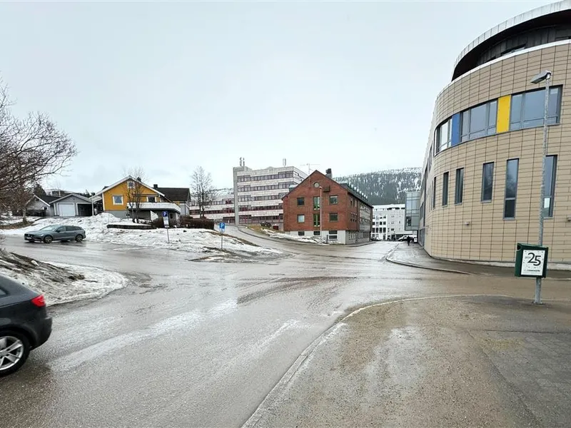 Veikryss omgitt av bygninger. Et par biler er sybnlig på bildet. Foto - Klikk for stort bilde
