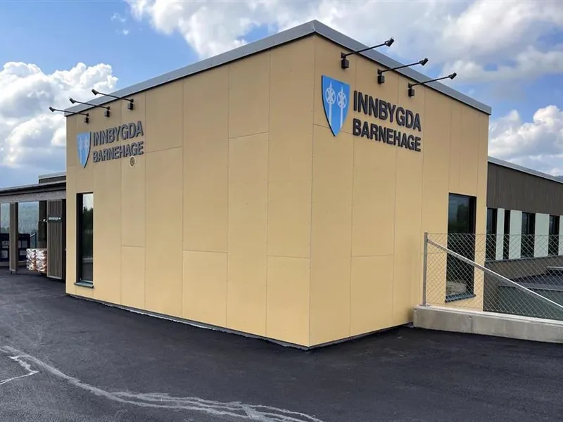 Deler av et bygg har gule fasadeplater med skilt på to av ytterveggene - Klikk for stort bilde