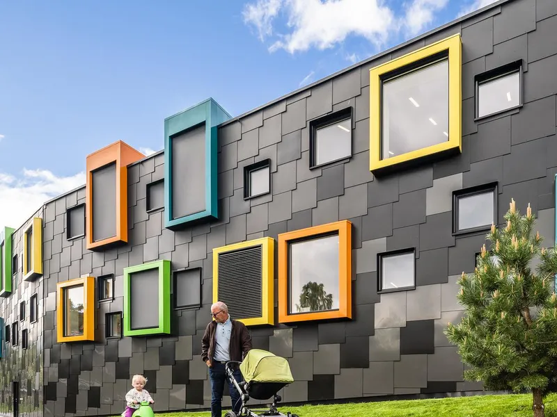 Fasade i mørk aluminium med firkantede vinduer i ulike sterke farger. Foto