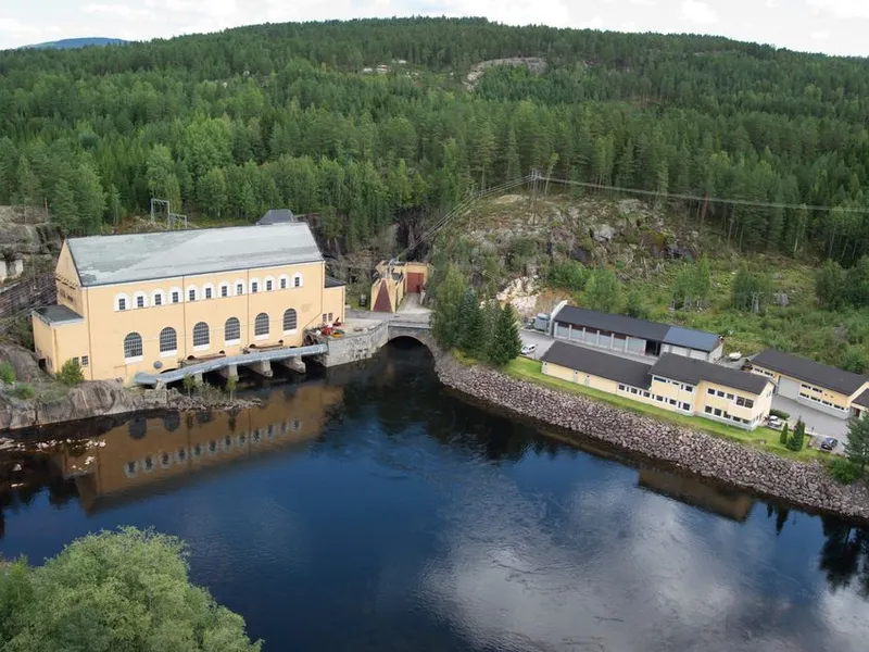 Kraftverk, vann, skog, kontorbygg, garasjebygg. Foto.