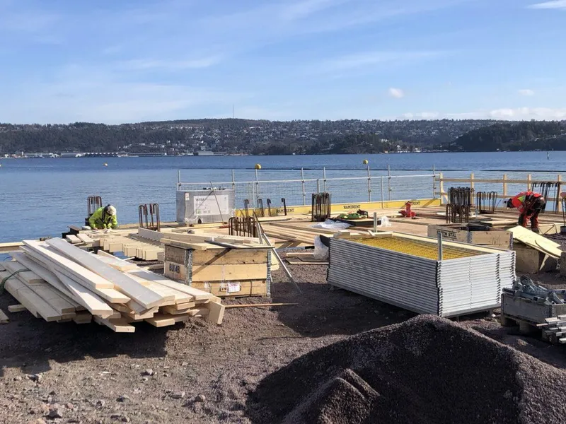 Langøyene på sommerstid. Strandområdet er fylt med byggematerialer som skal brukes i forbindelse med miljøtiltak