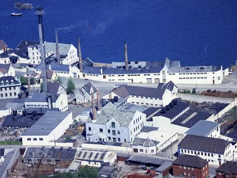 Tinnfabrikken, med sine lavere hvite fabrikkbygninger og 58 meter høye, spinkle tårn.