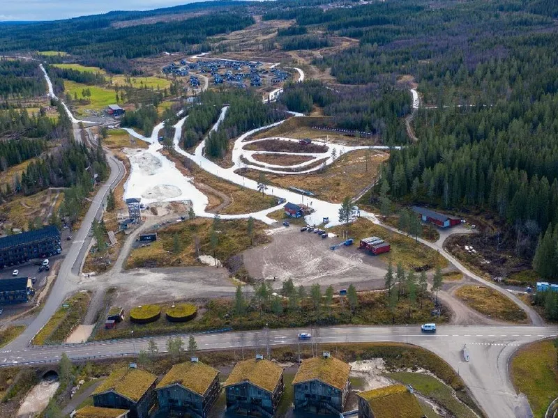 Dronebilde av område med skiløyper med tidligsnø, hytter og leilighetsbygg - Klikk for stort bilde