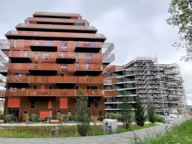 To boligblokker, grønne gangveier, blå himmel