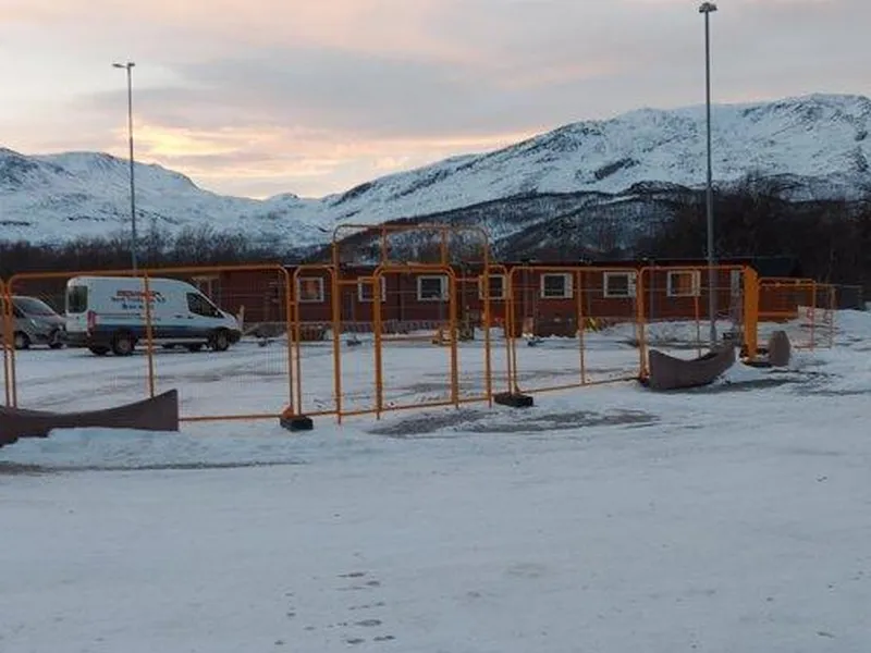 Gult anleggsgjerde ved området omkring Moan skole. Biler står parkert ved siden av brakkerigg. Det er en lys vinterdag.