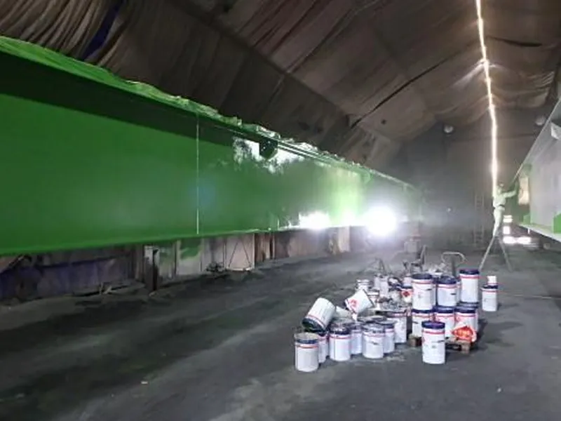 En hall med lang, stor stålbjelke langs vegg. Malingsstann på betonggolv. Foto. - Klikk for stort bilde