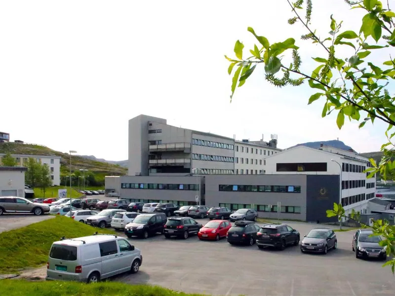 Hammerfest sykehus sett fra nordvest med parkeringsplass og biler i forgrunnen - Klikk for stort bilde