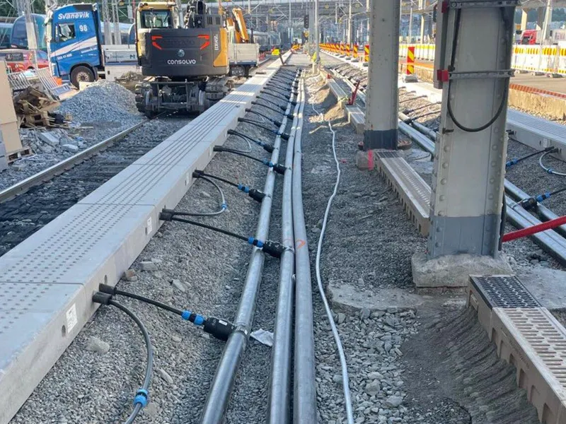 Svarte rør går inn i betongblokker på kanten av perrongen på en togstasjon