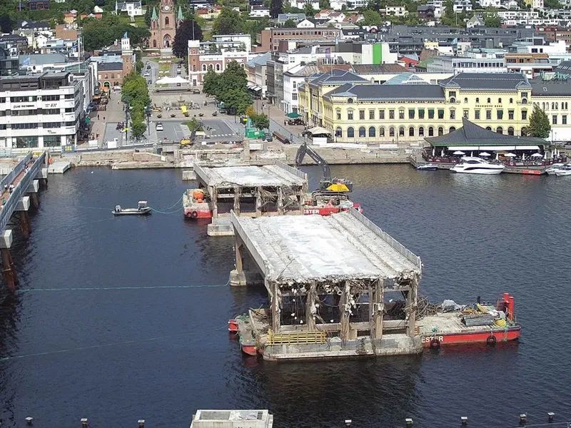 Rivingen av den gamle bybrua i Drammen har pågått siden i mai. Store deler av betongen fra rivearbeidene vil bli gjenbrukt som masser i fyllinger i det nye bybruprosjektet.Foto: Timelapskamera Drammen kommune.