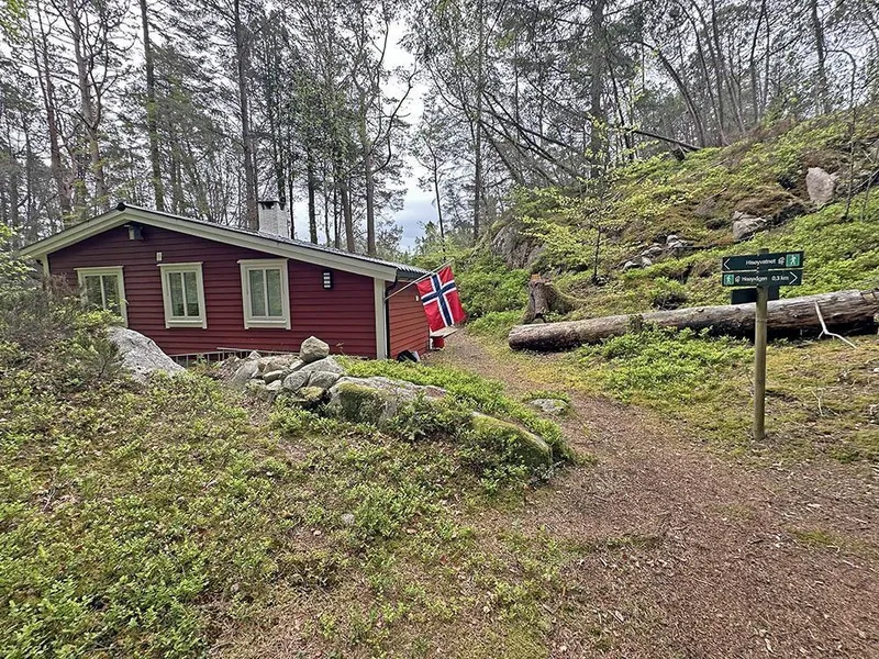 hytte i skog og turløypeskilt - Klikk for stort bilete