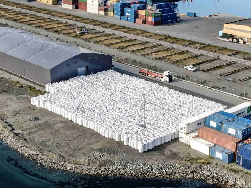 Lagerområde med hall og containere ved sjøkanten