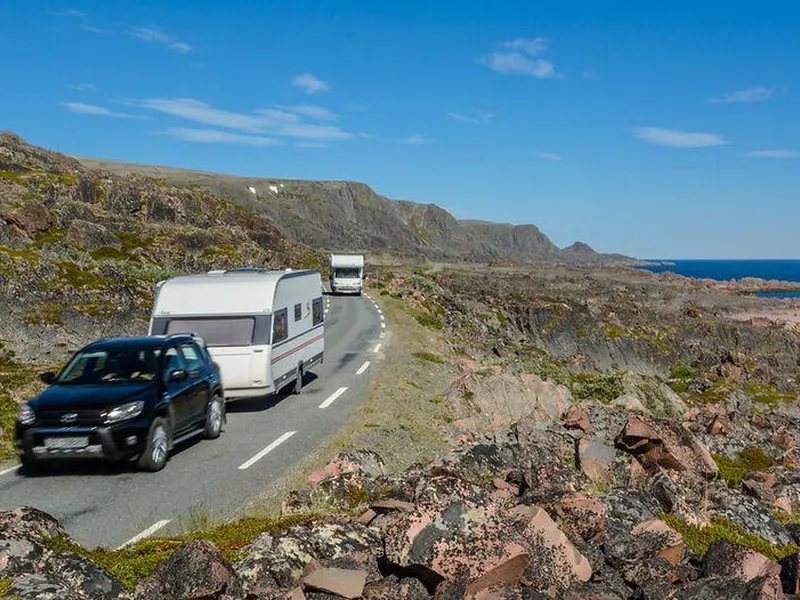Bil med campingvogn og en bobil kjører på turistvegen.