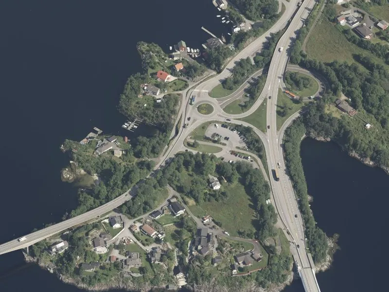 Dagens parkeringsplass er midt i biletet, like ved rundkøyringa. Ny parkeringsplass blir rett sør for denne. Foto: 1881.no