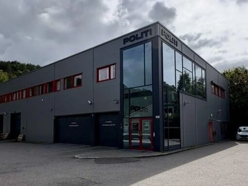 Et bygg i motlys, med Politi-skilt på veggen