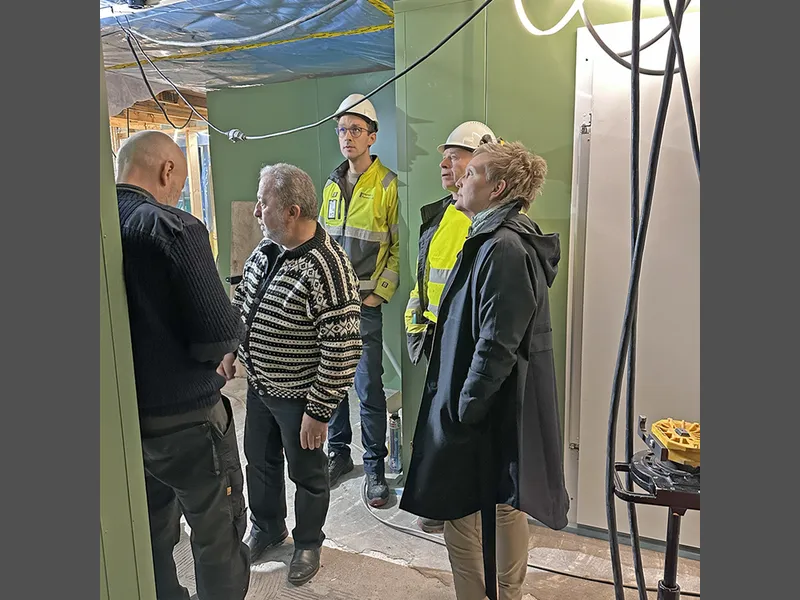 fire menn og ei kvinne på synfaring inne i byggeprosjekt - Klikk for stort bilete