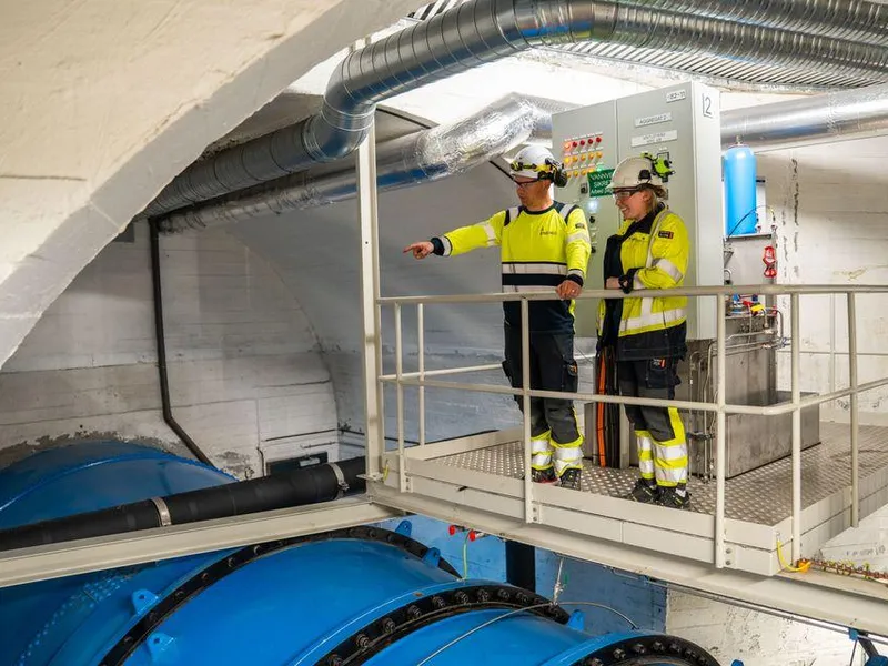To mennesker iført verneklær inne i en kraftstasjon. Foto.