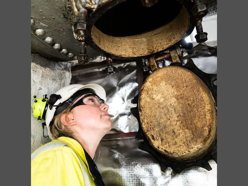 Dame iført verneutstyr inne i et kraftverk. Foto.