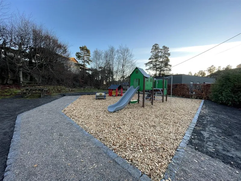Lekeplass med lekeapparater, benker og adkomstvei i grus - Klikk for stort bilde