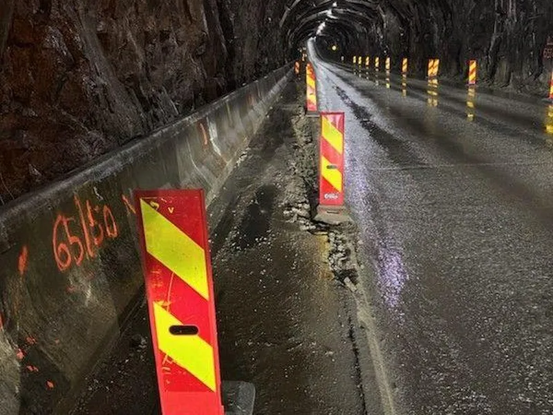 Bildet viser en tomm tunnel merket med reflekser som viser hvor kjørebanen går. Bildetksten sier, Stopper arbeidet i fellesferien: Arbeidet med å oppgradere Nappstraumtunnelen stoppes av praktiske grunner i perioden med høyest trurristtrafikk i Lofoten.