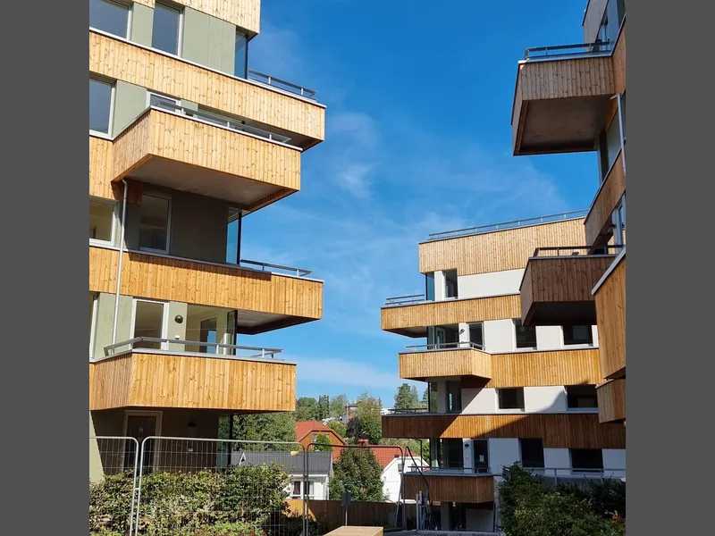 Boligbygg i 3-4 etasjer, balkonger med trebekledning, blå himmel
