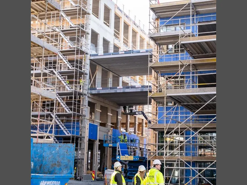 Tre mennesker og byggeplass. Foto - Klikk for stort bilde