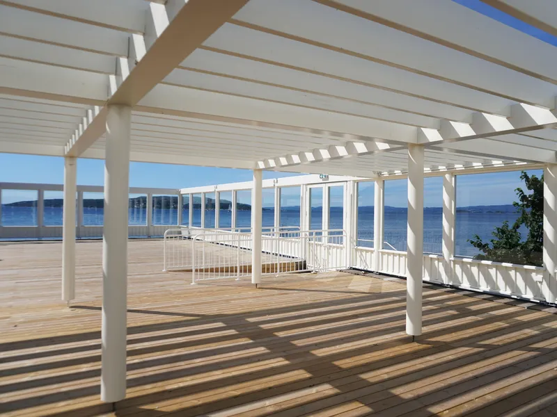 Terrasse med pergola over deler av terrassen, utsikt mot havet.