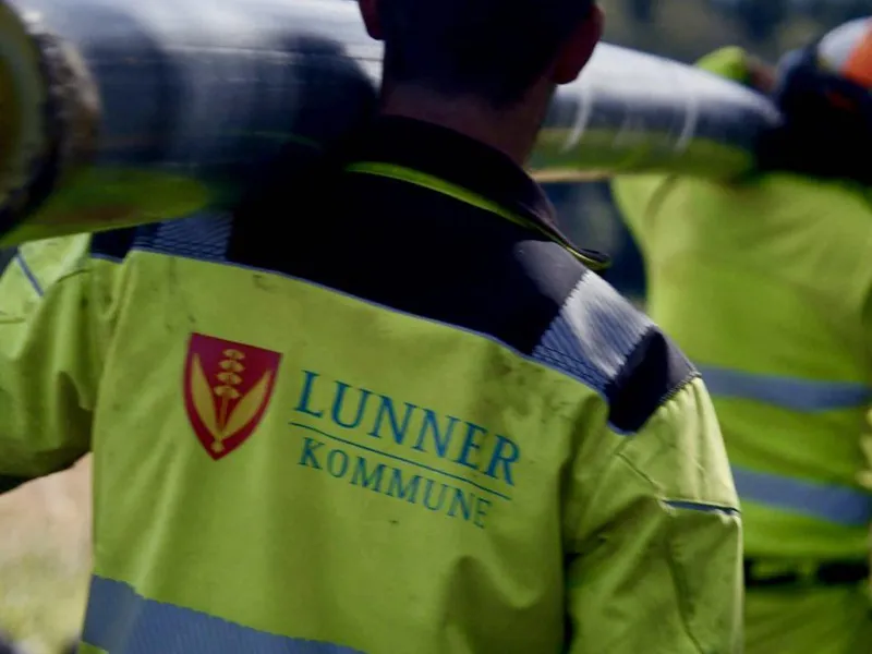 Bilde av ansatt med gul Lunnerjakke som bærer på et rør