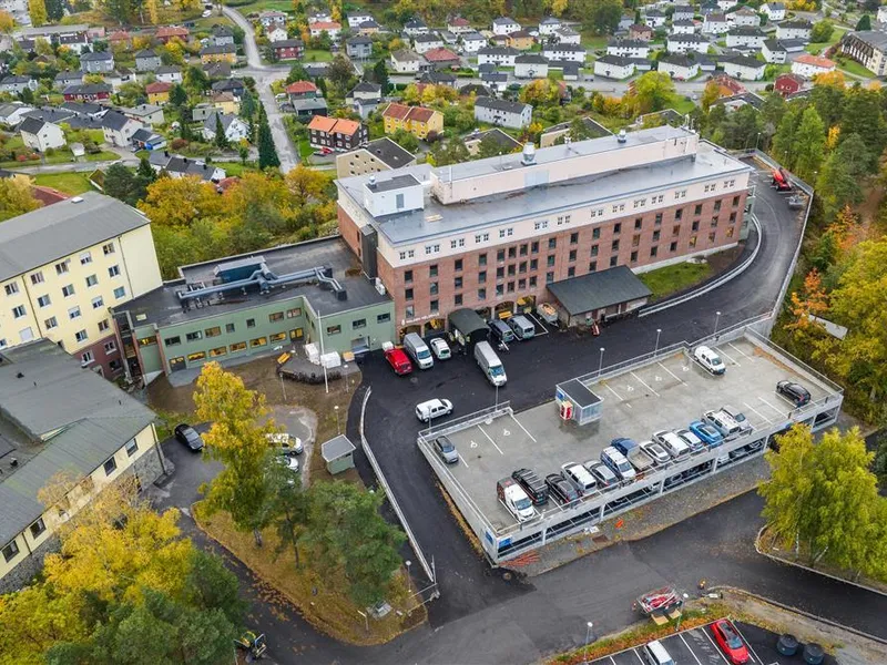 Dronebilde av stort institusjonsbygg i 4-5 etasjer. - Klikk for stort bilde